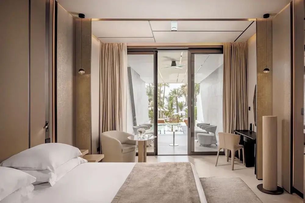 Schlafzimmer mit Blick durch große Schiebetüren auf die Terrasse mit privatem Pool.