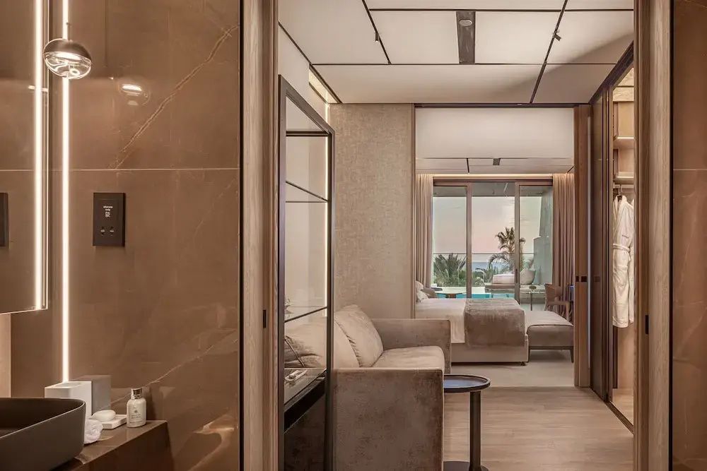 Blick durch den modernen Wohnbereich einer Hotel-Suite auf das Schlafzimmer und die Terrasse.