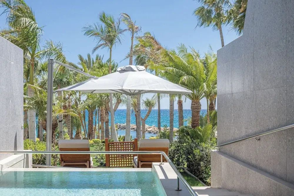 Privater Pool auf der Terrasse mit Sonnenschirm, Liegen und Blick auf das Meer.