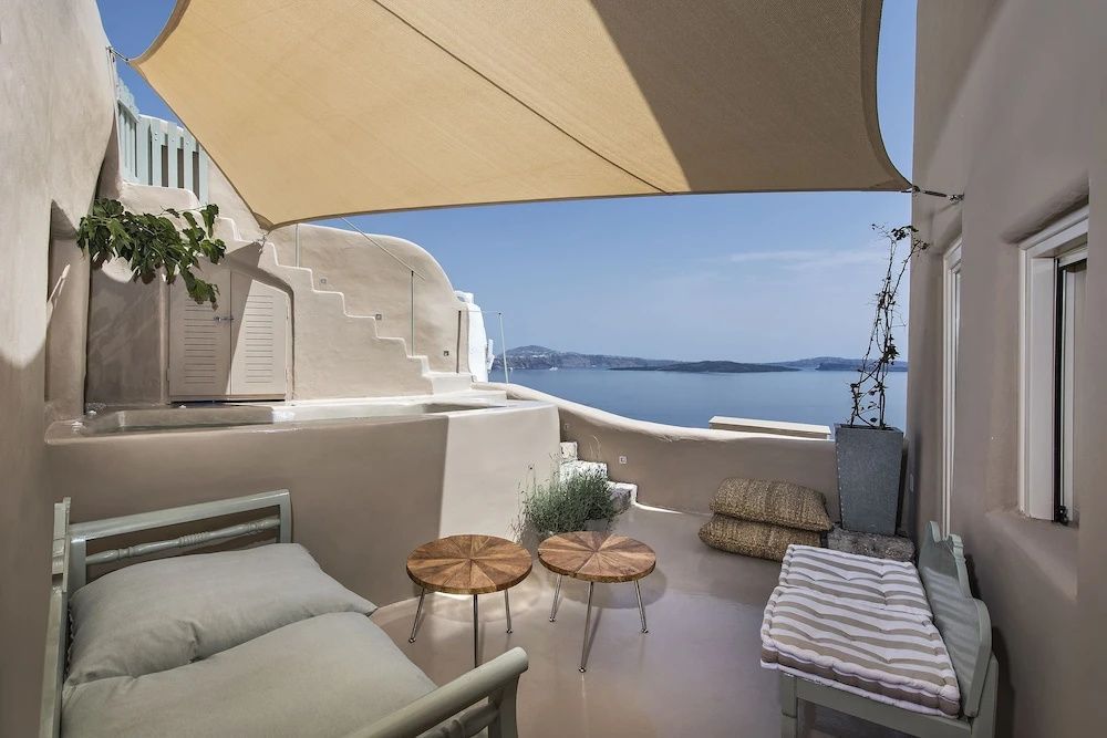 Überdachte Terrasse mit Holzmöbeln und freiem Blick auf das Meer und die Vulkaninseln.