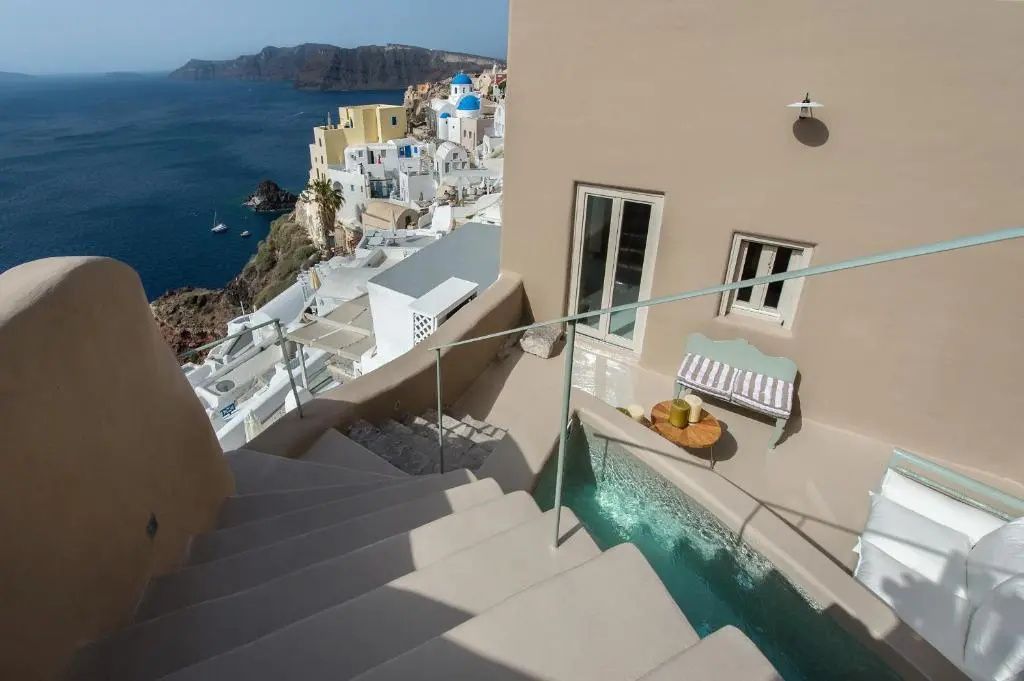 Außentreppe zu einem kleinen Pool auf der Terrasse mit Blick auf Oia und das Meer.