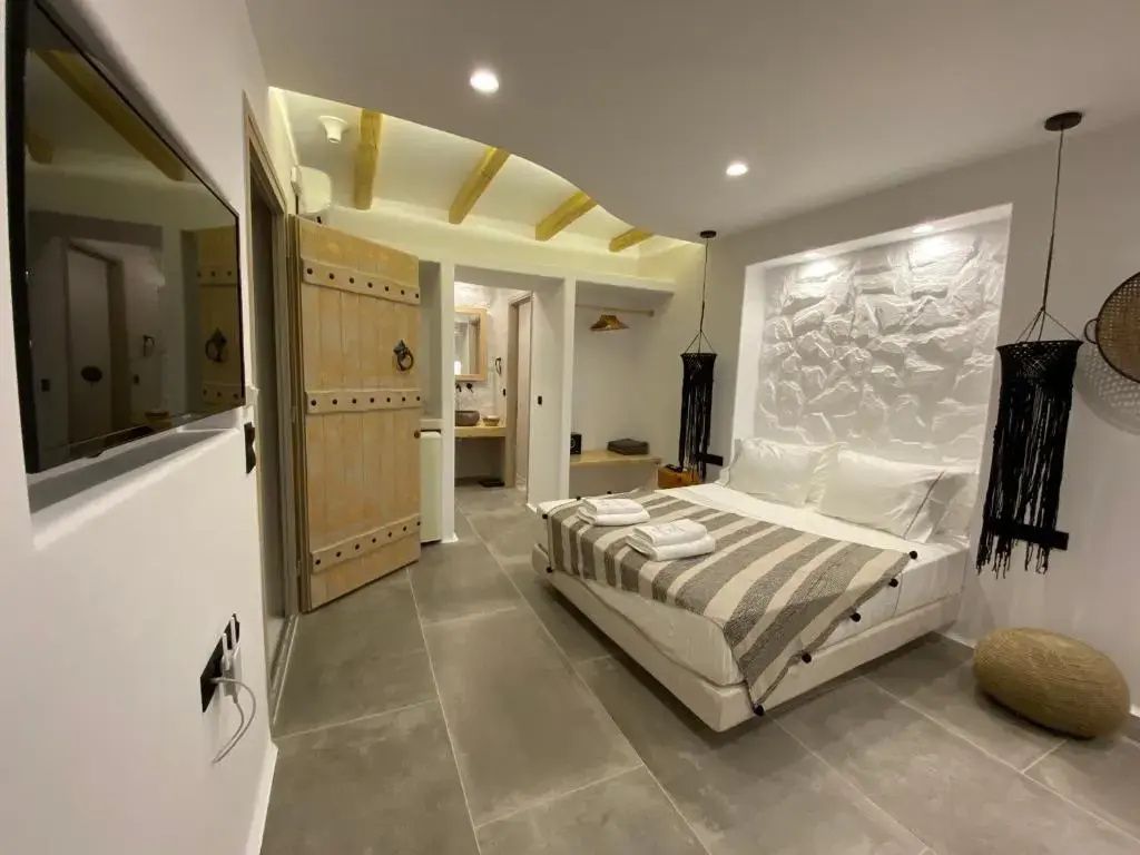 Hotelzimmer mit Doppelbett, weiß gekalkter Steinwand, Holzdecke und einer rustikalen Holztür.