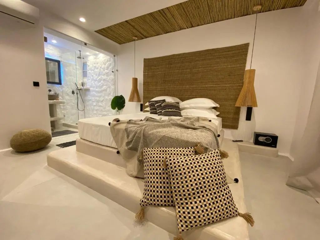 Helles Schlafzimmer mit Holzkopfteil, Podestbett und integriertem Badbereich.