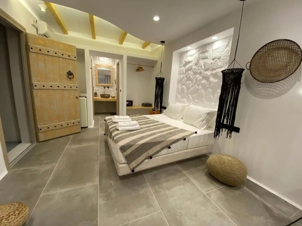 Hell gestaltetes Zimmer mit Doppelbett, Struktursteinwand und Blick in das Badezimmer.