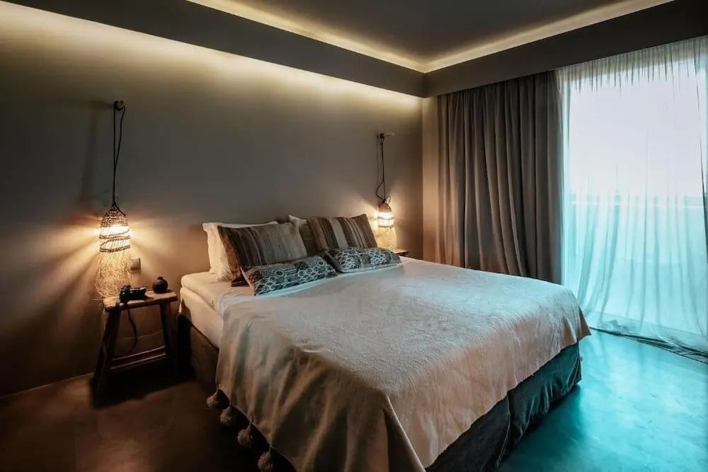 Doppelbett mit hellem Überwurf und gemusterten Kissen in einem modern eingerichteten Hotelzimmer