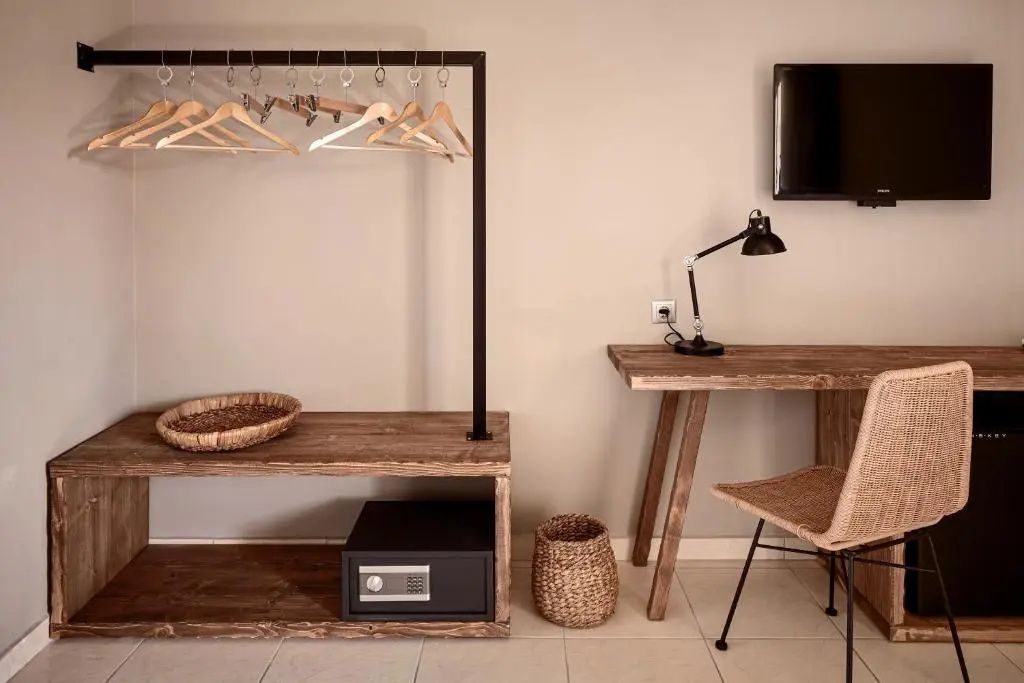 Offener Kleiderständer aus Holz, ein kleiner Safe, ein Schreibtisch mit Lampe und Stuhl im Hotelzimmer.