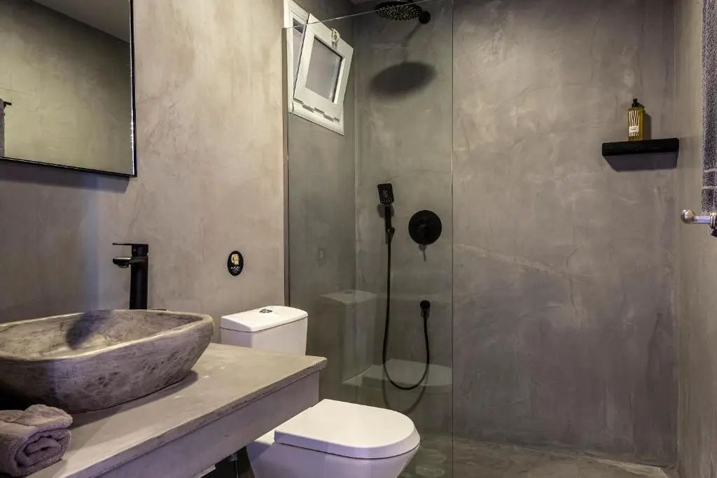 Modernes Badezimmer in Grautönen mit bodengleicher Glasdusche, Regendusche und Steinwaschbecken.