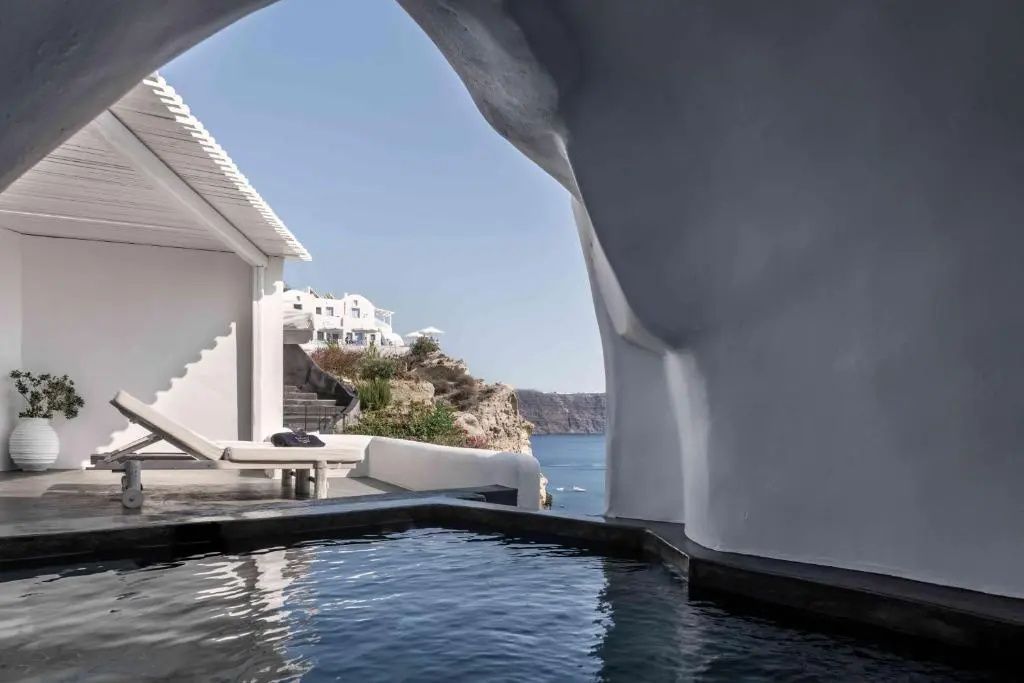 Kleiner Pool auf einer weißen Terrasse mit Blick auf das Meer und die Küste.
