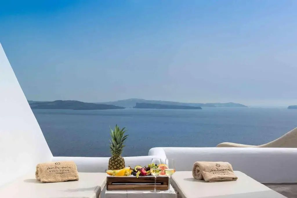 Terrasse mit Sonnenliegen, Früchteplatte und freiem Blick auf das blaue Meer.