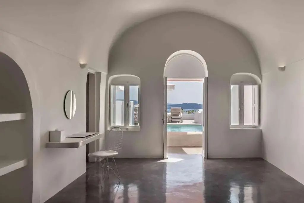 Zimmer mit offener Tür und Fenstern, die den Blick auf den Pool und das Meer freigeben.