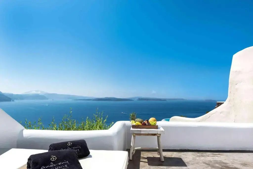 Weiß umrandete Terrasse mit Liegestühlen und Panoramablick auf das Meer.