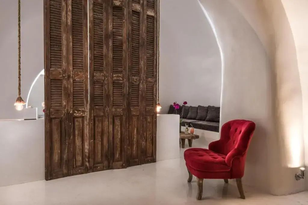 Roter Sessel vor einer rustikalen Holzwand in einem hell gestalteten Gewölberaum.