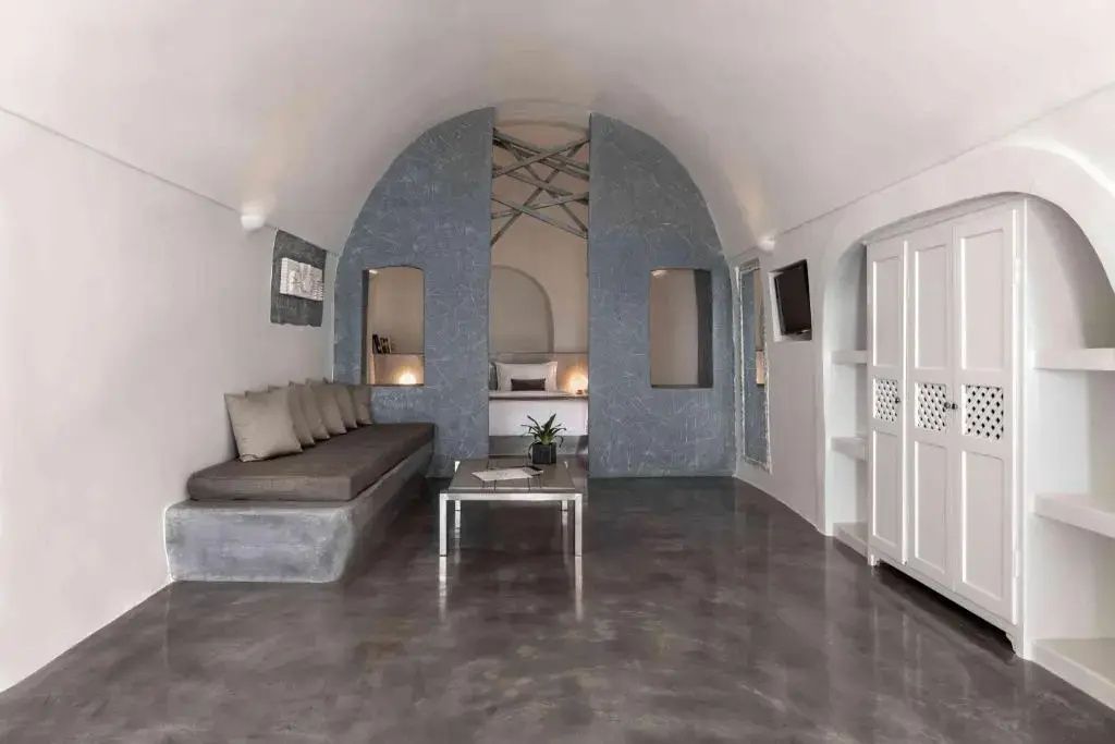 Offene Suite mit Gewölbedecke, Sitzgelegenheit, Couchtisch und hellem Kleiderschrank.