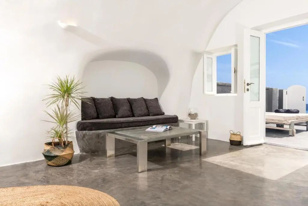 Wohnbereich mit gepolsterter Sitzbank, Glas-Couchtisch und Zimmerpflanze.