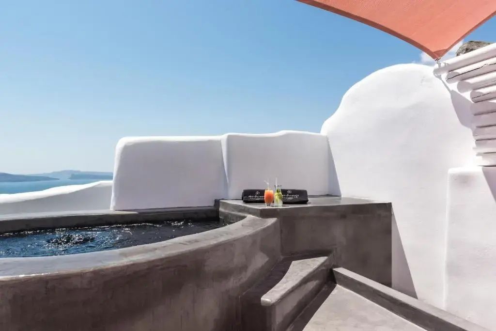 Ein Whirlpool auf einer Terrasse mit weiß gekalkten Mauern und freiem Blick auf das Ozeanwasser.