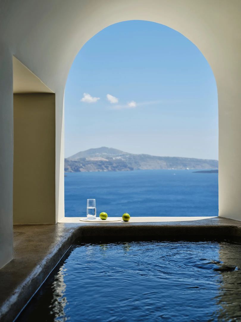 Überdachter Pool mit verputztem Rundbogen und freiem Blick auf das Meer und die Vulkaninseln.