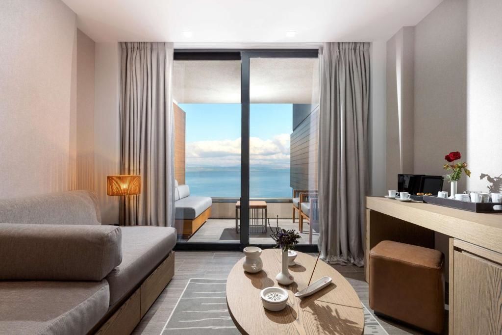 Blick aus dem Zimmer auf einen überdachten Balkon mit Sitzgelegenheit und Meer