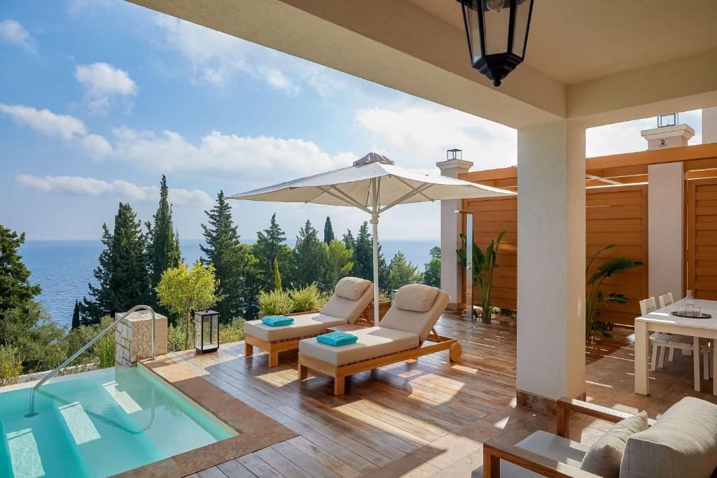Überdachte Terrasse mit Holzfußboden, Liegestühlen, Sonnenschirm und Aussicht auf Meer und Natur.