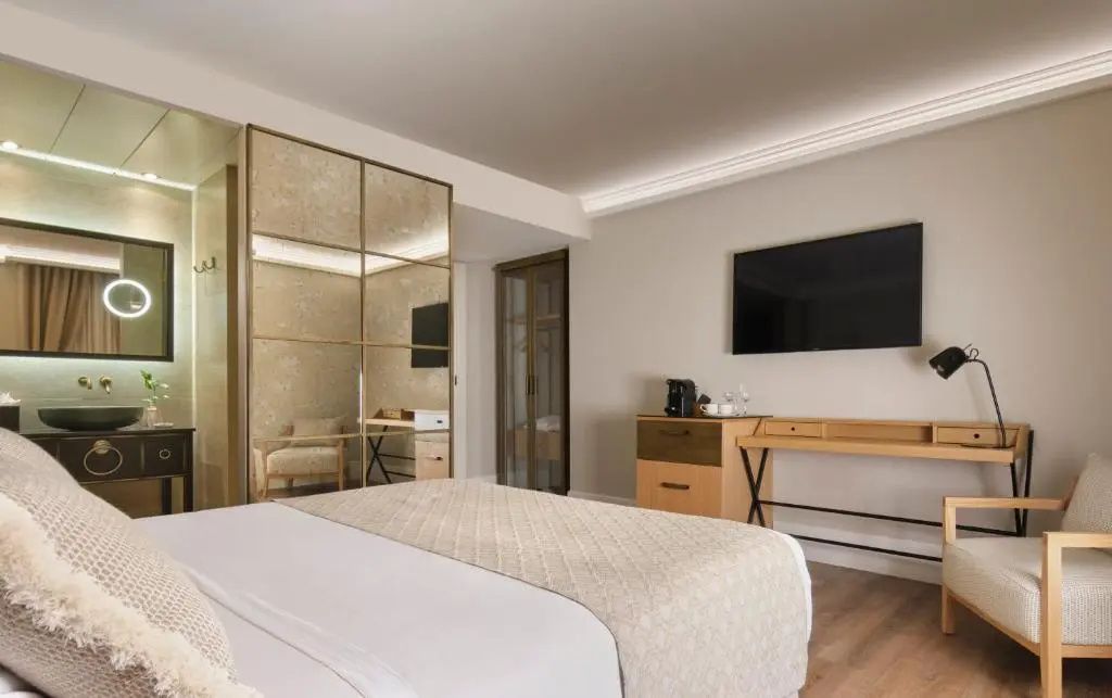 Hotelzimmer mit großem Bett, Fernseher an der Wand, Schreibtisch und verspiegeltem Schrank.