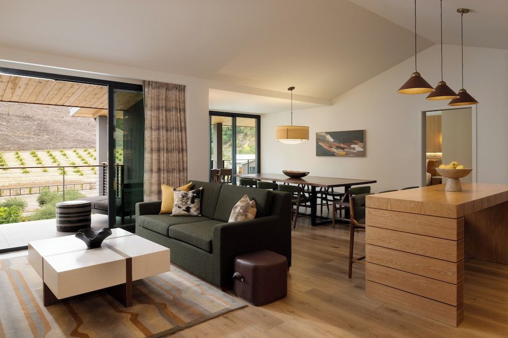 Grünes Sofa, Couchtisch und Esstisch in einem offenen Wohnraum mit Zugang zum Balkon.