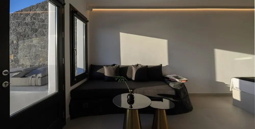 Sitzbereich im Zimmer mit dunkelgrauem Sofa, Kissen und zwei kleinen Beistelltischen.