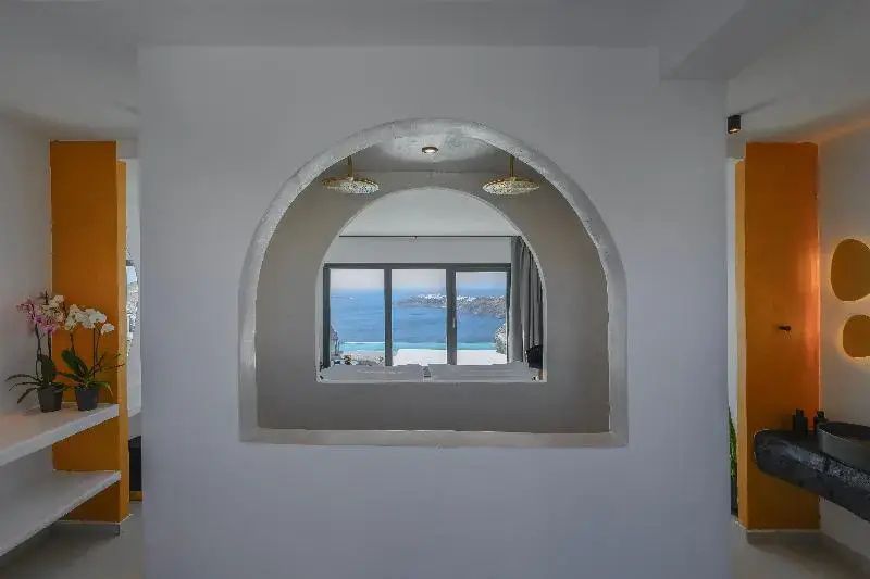 Blick durch eine rundbogige Wandöffnung auf ein großes Fenster mit Meeresaussicht.