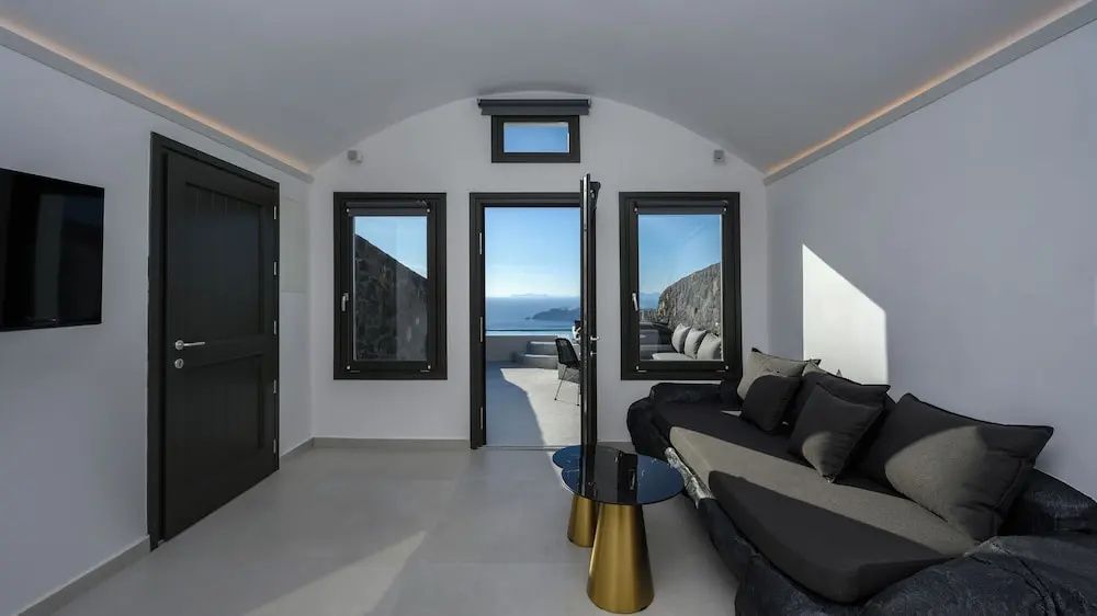 Blick aus dem hellen Zimmer durch eine geöffnete Tür auf eine Terrasse und das Meer.
