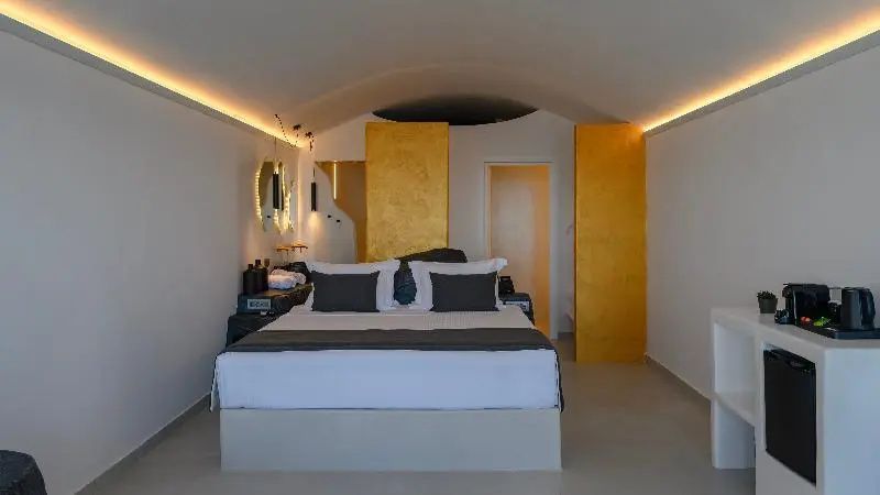 Schlafbereich mit weißem Doppelbett, gewölbter Decke, Beleuchtung und goldenen Raumteilen.