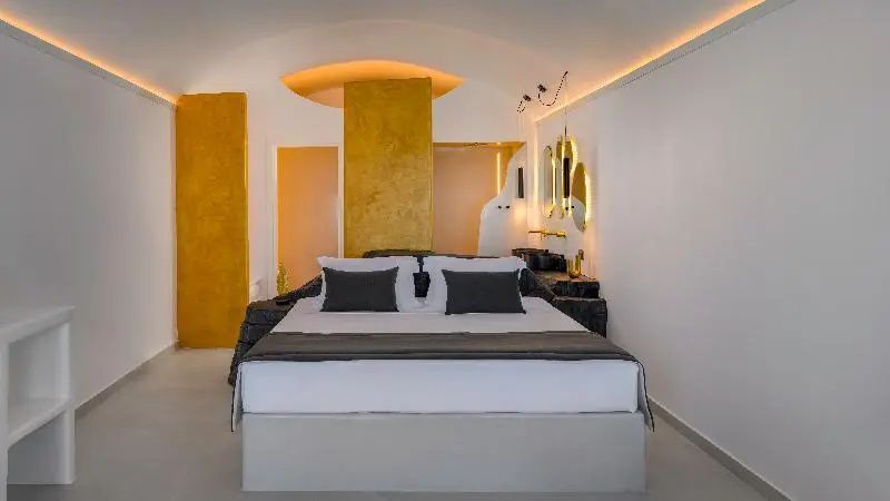 Modernes Hotelzimmer mit großem Doppelbett und gelben beziehungsweise goldenen Wandakzenten.