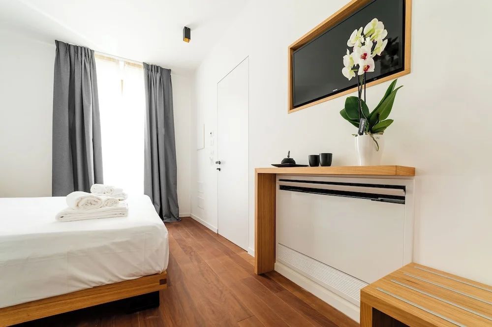 Modernes Hotelzimmer mit Holzboden, Doppelbett, Wandfernseher und weißer Orchidee.