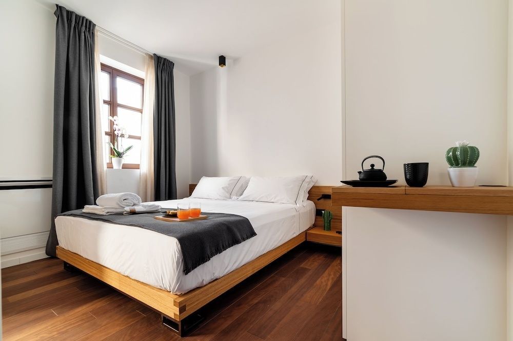 Doppelbett aus Holz mit weißer Bettwäsche, Holzfußboden und Holzfenster im Schlafzimmer.