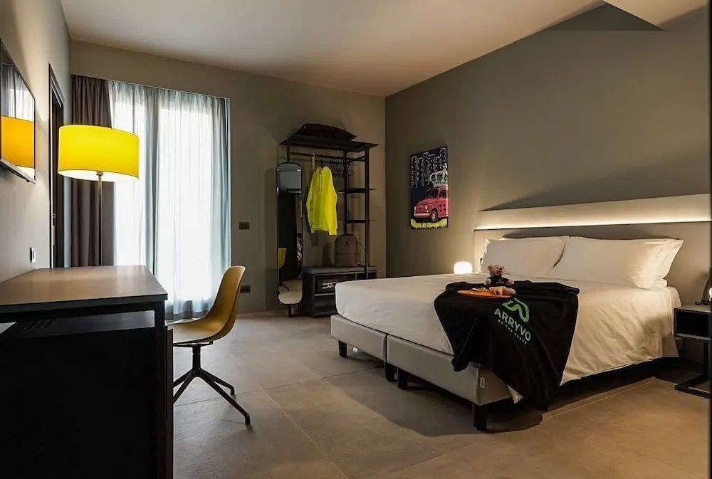 Moderner Hotelraum mit Doppelbett, gelbem Schreibtischstuhl und offenem Kleidergestell.
