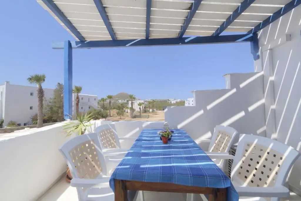 Überdachte Terrasse mit blau kariertem Esstisch, Stühlen und Ausblick auf die Umgebung.