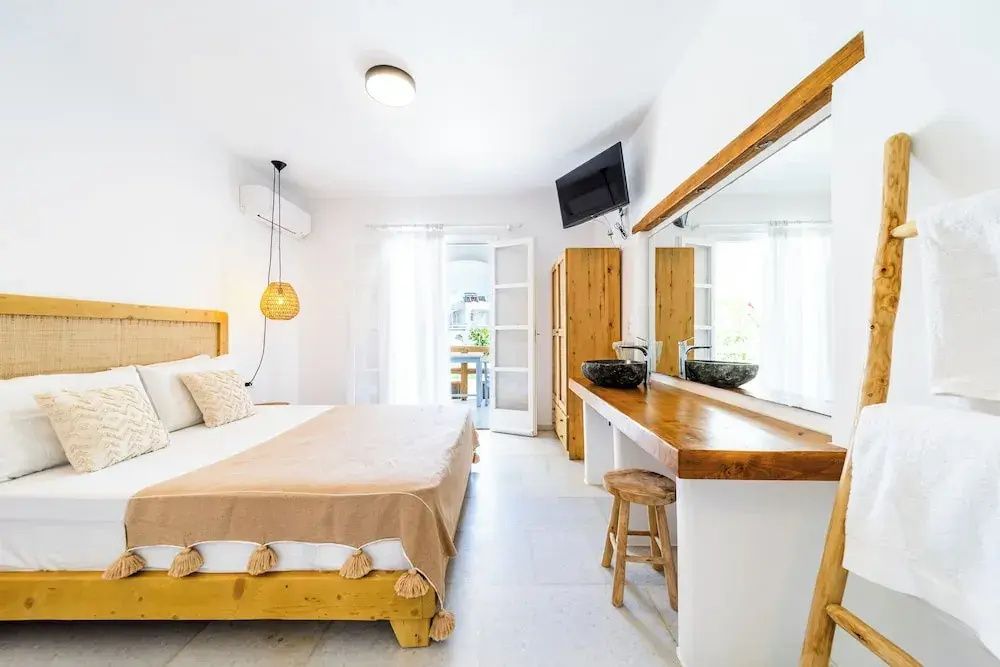 Helles Studiozimmer mit Doppelbett, Holzschreibtisch, großem Spiegel und Balkonzugang.