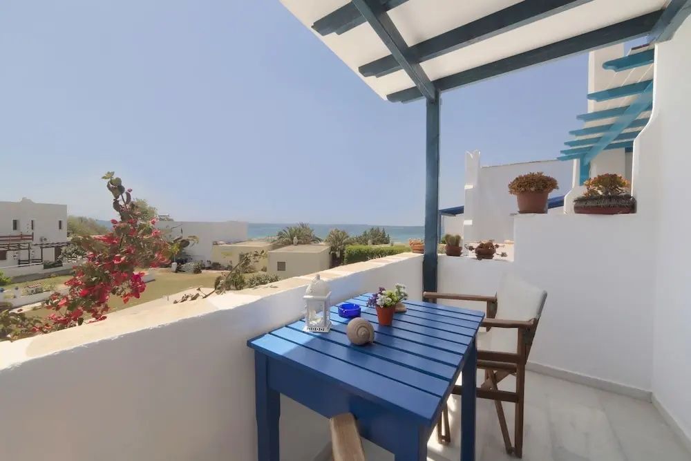 Balkon mit blauem Tisch und Blick auf das Meer und umliegende Gebäude.