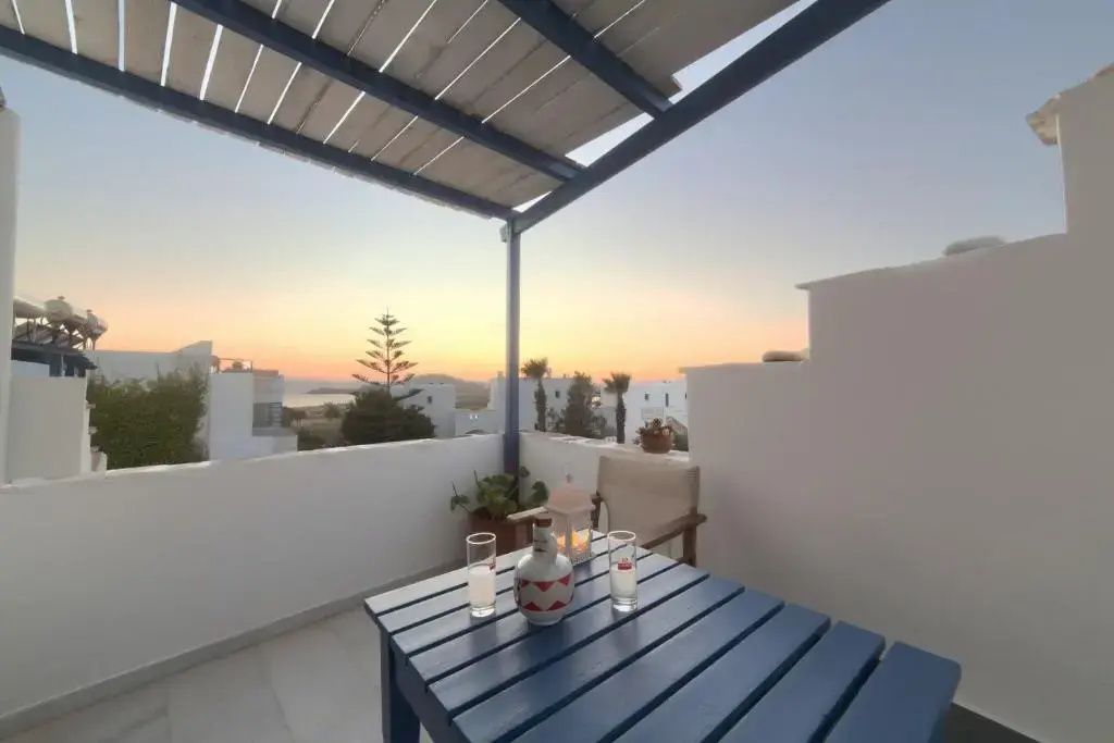 Terrassentisch mit Gläsern vor der Silhouette der Küstenlandschaft im Abendlicht.