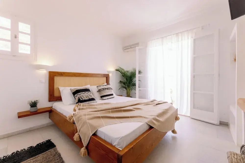 Ein großes Doppelbett aus Holz mit Kissen, Tagesdecke und einer Zimmerpflanze.