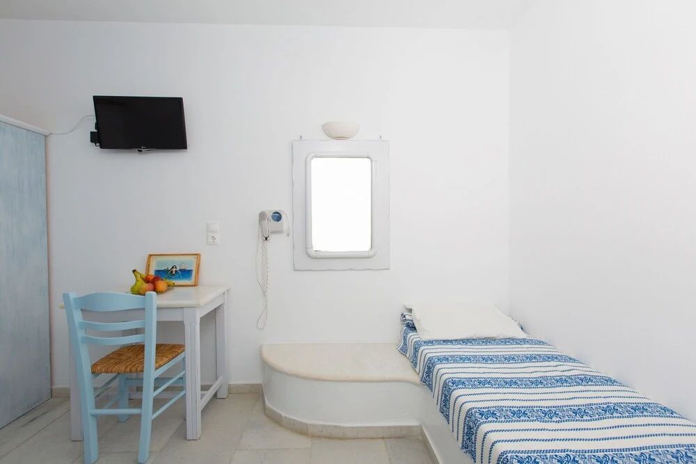 Schlafbereich mit eingebautem Einzelbett, kleinem Tisch und Fenster an weisser Wand