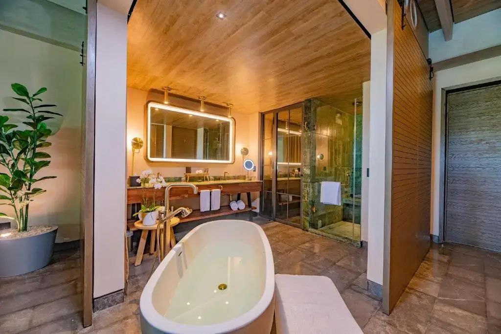 Badezimmer mit freistehender Badewanne, Beleuchtung am Spiegel und Dusche.