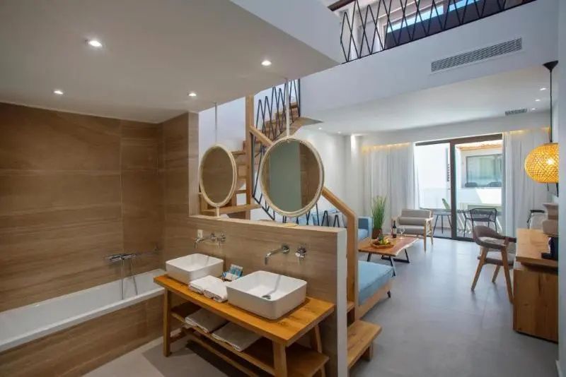 Zweigeschossige Suite mit offenem Badezimmerbereich, Doppelwaschbecken und Treppe.