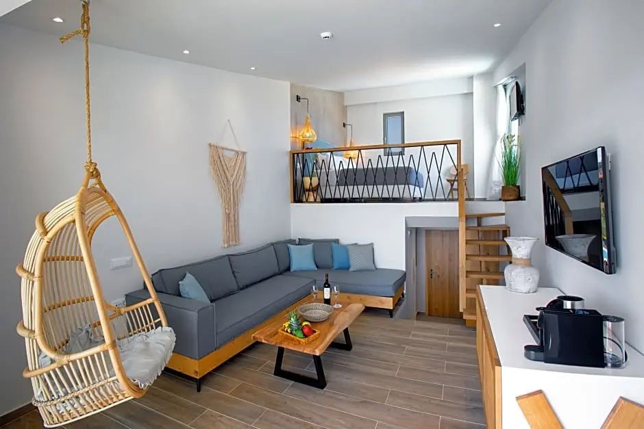 Wohnbereich einer Suite mit grauer Eckcouch, Holztisch und Treppe zur Empore