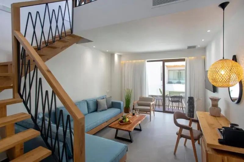 Wohnbereich mit blauer Couch, Holztisch, Holztreppe und Zugang zum Balkon.