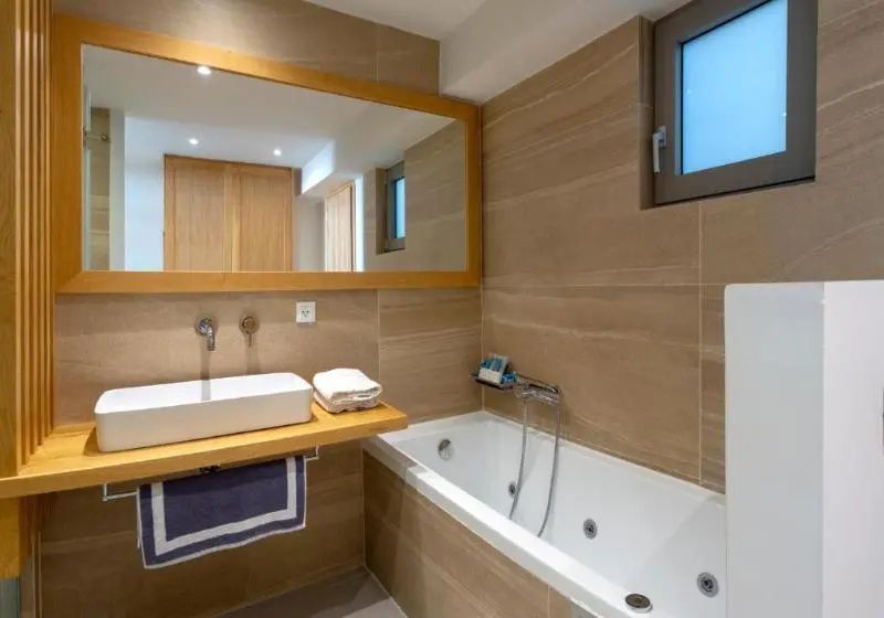 Badezimmer mit einer weißen Badewanne, Aufsatzwaschbecken und große Spiegelfläche.
