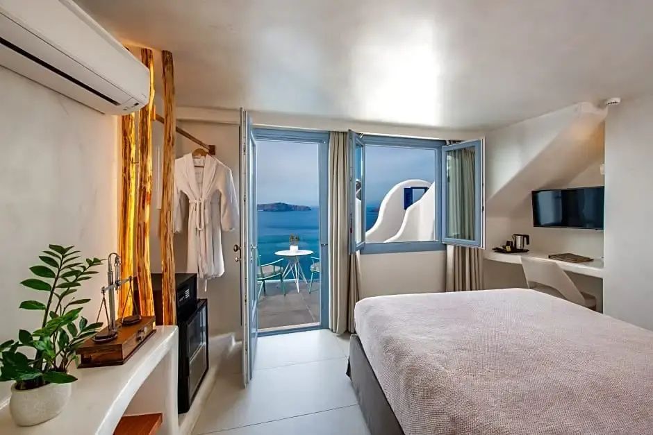 Hell eingerichtetes Hotelzimmer mit Doppelbett und geöffneter Tür zur Terrasse mit Meerblick.