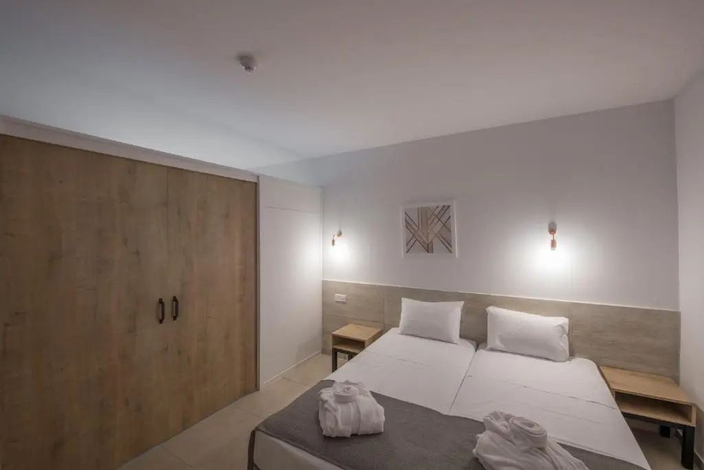 Schlafbereich im Hotelzimmer mit zwei Betten, Holzschrank und Bademänteln
