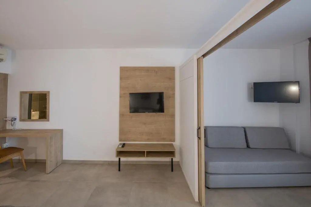 Wandmontierter Fernseher auf Holzpaneel neben dem Durchgang zum Wohnbereich