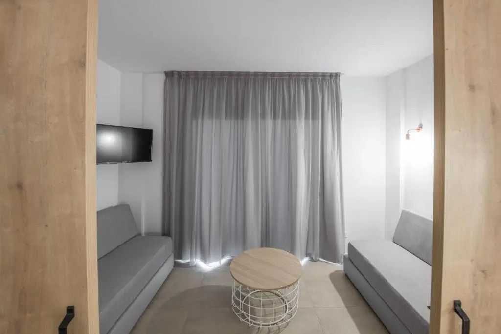 Sitzbereich mit zwei grauen Sofas, rundem Couchtisch und verhangenem Fenster