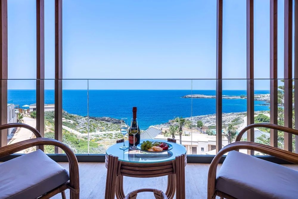 Tisch mit Getränken auf dem Balkon vor einer Glasscheibe mit freiem Meerblick.