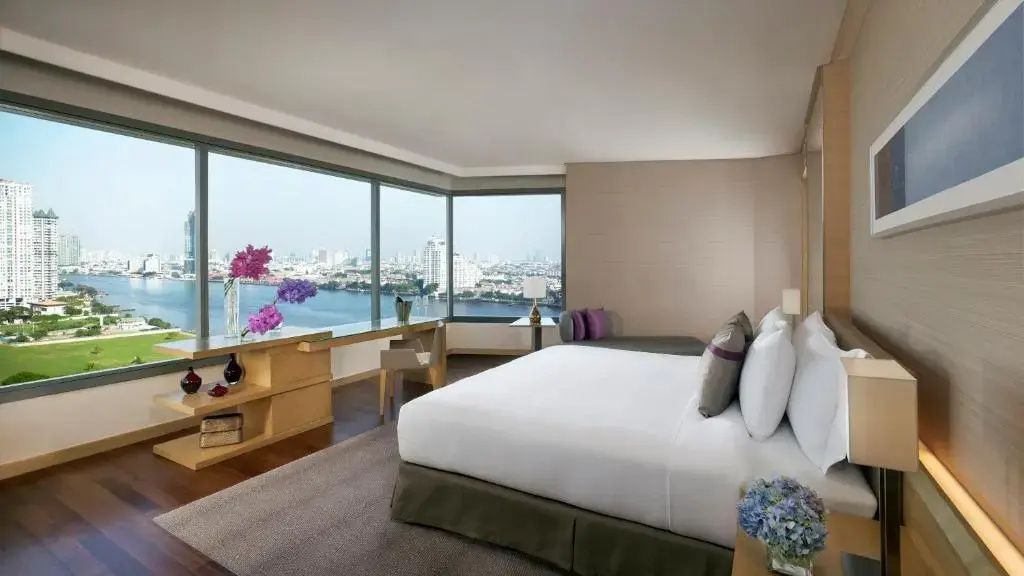 Hotelzimmer mit großem Doppelbett und Panoramafenster mit Blick auf den Fluss.