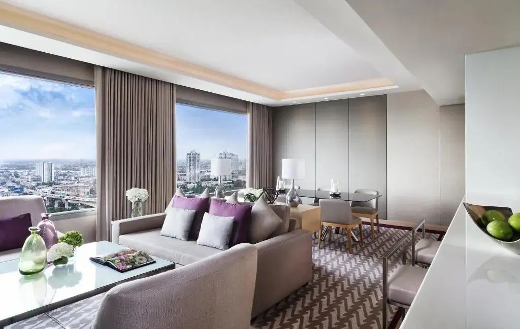 Geräumiger Wohnbereich mit beigefarbenem Sofa, Sessel und Blick auf die Stadt.